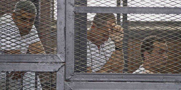 Mohammed Fahmy, Canadian-Egyptian acting bureau chief of Al-Jazeera, from left, Australian correspondent Peter Greste and Egyptian producer Baher Mohamed appear in a defendant's cage along with several other defendants during their trial on terror charges at a courtroom in Cairo, Egypt, Thursday, May 15, 2014. Three lawyers representing Al-Jazeera English journalists on trial in Egypt abruptly have quit the case, accusing the Doha-based network of using the arrest of their staff to tarnish Egyptâs image. (AP Photo/Hamada Elrasam)