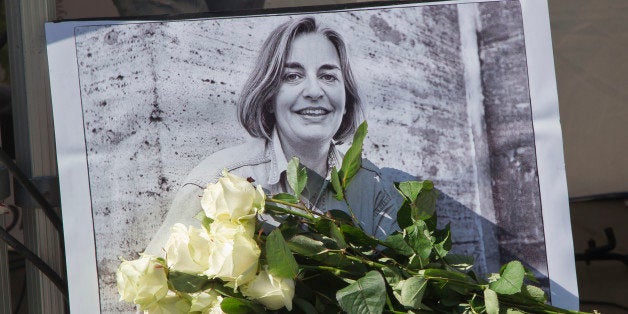 FILE - In this Saturday, April 5, 2014 file photo, roses lay in front of a picture of the Associated Press photographer Anja