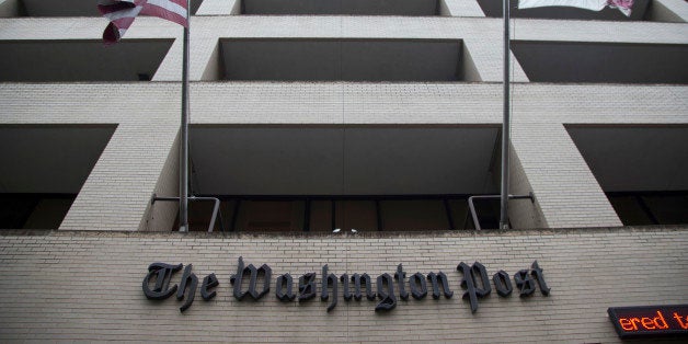 FILE - In this Aug. 6, 2013, file photo, an American flag, left, and a District of Columbia fly outside The Washington Post building in Washington. The longtime headquarters building of The Washington Post is being sold to a real estate development company for $159 million. Graham Holdings Co. is the former parent of The Washington Post newspaper. The company announced a deal Nov. 27, to sell the downtown Washington building to Carr Properties. (AP Photo/Evan Vucci, File)