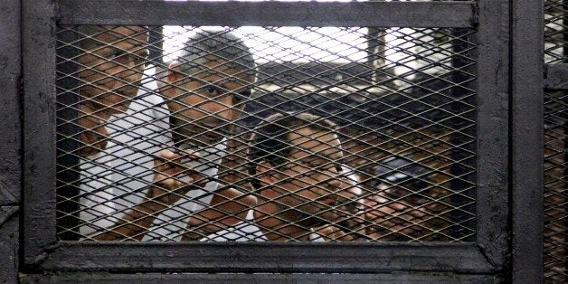 From left, Australian correspondent Peter Greste, Canadian-Egyptian acting bureau chief of Al-Jazeera Mohamed Fahmy, and Egyptian producer Baher Mohammed, appear in a defendant's cage in a courtroom in Cairo, Egypt, Monday, June 23, 2014. An Egyptian court on Monday convicted three journalists from Al-Jazeera English and sentenced them to seven years in prison each on terrorism-related charges, bringing widespread criticism that the verdict was a blow to freedom of expression. The three, Greste, Fahmy and Mohammed, have been detained since December charged with supporting the Muslim Brotherhood, which has been declared a terrorist organization, and of fabricating footage to undermine Egypt's national security and make it appear the country was facing civil war. (AP Photo/Heba Elkholy, El Shorouk Newspaper) EGYPT OUT