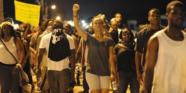 Protesters walk take part in a peaceful protest down a street in Ferguson, Missouri on August 19, 2014. Police lowered their