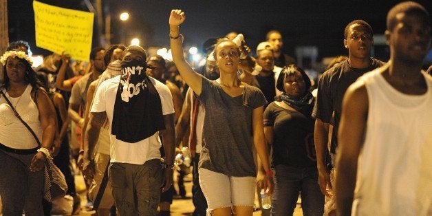 Protesters walk take part in a peaceful protest down a street in Ferguson, Missouri on August 19, 2014. Police lowered their profile on August 19, and refrained from using tear gas, to allow a more orderly night of protests in this St Louis suburb 10 days after the police shooting of an unarmed black teenager. AFP PHOTO / Michael B. Thomas (Photo credit should read Michael B. Thomas/AFP/Getty Images)