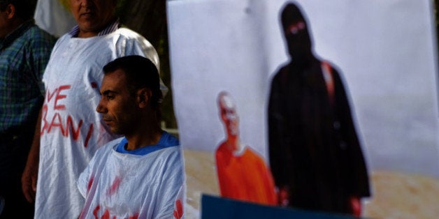 Kurdish protesters wearing aprons calling for support to save the Syrian town of Kobani from being overrun by Islamic State group fighters are seen next to a photograph of American journalist James Foley who was killed by the extremist group during a demonstration outside the Parliament of Cyprus in the capital Nicosia on Tuesday, Oct. 7, 2014. Kurdish protesters gathering outside of the parliament to call for help for the town of Kobani on the Syrian-Turkish border. (AP Photo/Petros Karadjias)