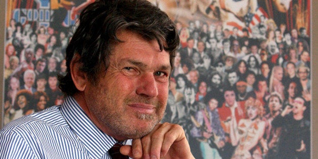 Rolling Stone publisher Jann Wenner poses for a portrait with a reproduction of the cover of the magazine's 1000th issue, Tuesday, May 2, 2006 in his New York office. (AP Photo/Mary Altaffer)