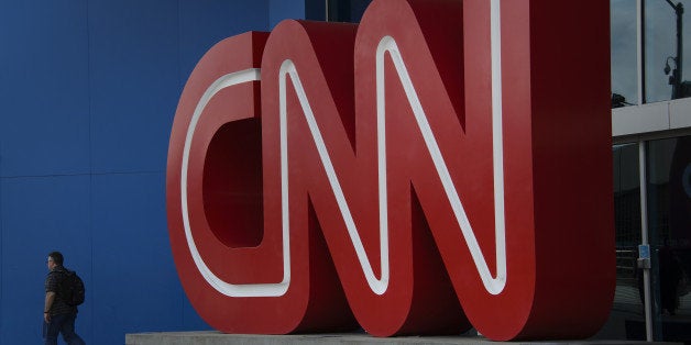 A pedestrian passes in front of CNN signage displayed at the network's headquarters building in Atlanta, Georgia, U.S., on Friday, Aug. 1, 2014. Time Warner is a 'long, long way from a transaction,' former Chief Executive Officer Richard Parsons said, adding the home of HBO, CNN and the Warner Bros. studio would be better off remaining independent. Photographer: Michael A. Schwarz/Bloomberg via Getty Images