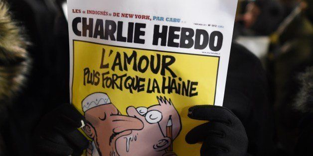 A man holds a cartoon as people gather on Union Square January 7, 2015 in New York in memory of the victims of the attack on the offices of the satirical weekly Charlie Hebdo in Paris. US President Barack Obama condemned the 'cowardly, evil' assault on a French satirical newspaper that left 12 dead, pledging US assistance to Paris to bring the attackers to justice. AFP PHOTO / DON EMMERT (Photo credit should read DON EMMERT/AFP/Getty Images)