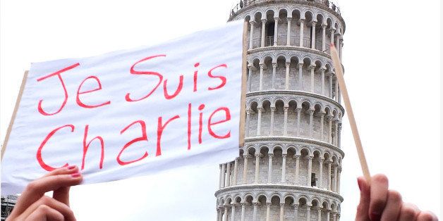 A woman holds a pencil and a poster reading in French "I am Charlie" during a rally in support of Charlie Hebdo, a French satirical weekly newspaper that fell victim to a terrorist attack in Paris, in front of the Leaning Tower of Pisa, Italy, Sunday, Jan. 11, 2015. Masked gunmen stormed the Paris offices of a weekly newspaper that caricatured the Prophet Muhammad, methodically killing 12 people Wednesday, including the editor, before escaping in a car. (AP Photo/Fabio Muzzi)
