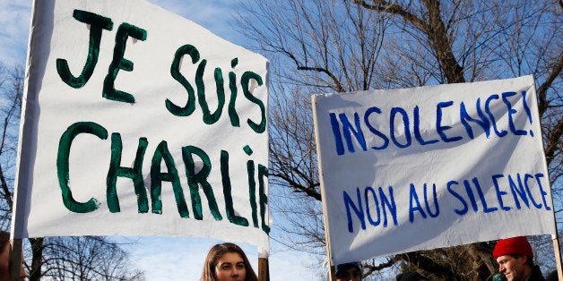 BOSTON - JANUARY 11: Lucy Brown, 16, of Cumberland, ME, holds a 'Je Suis Charlie' sign as her brother Nico, 14, and father Mark, 45, hold a sign that says 'Insolence! Non Au Silence' during a memorial service for French terror victims on the Boston Common in Boston on January 11, 2015. (Photo by Jessica Rinaldi/The Boston Globe via Getty Images)