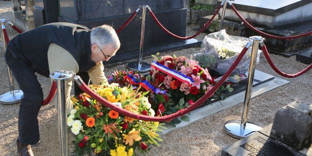 A man puts flowers on the tomb of Charlie Hebdo cartoonist Jean Cabut, known as Cabu, who was buried earlier Wednesday, in the Chalons-en-Champagne cemetery, eastern France, Wednesday Jan. 14, 2015. The core of the irreverent newspaper's staff perished a week ago when gunmen stormed its offices, killing 12 people and igniting three days of bloodshed around Paris. Charlie Hebdo employees who survived the massacre published a new issue of the magazine becoming known as the survivor's issue that appeared on the streets Wednesday with a print run of 3 million, more than 50 times the paper's usual circulation. (AP Photo/Remy de la Mauviniere)