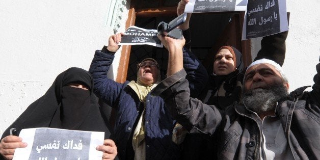 Algerian protestors hold up placards during a demonstration against French satirical weekly Charlie Hebdo for publishing a cartoon of the Muslim prophet Mohammed on January 16, 2015 in the capital Algiers. Between 2.000 and 3.000 take part in the protest as Muslims marched as well in Middle Eastern cities against the latest cartoon published by Charlie Hebdo featuring the Prophet Mohammed on its cover holding a 'Je Suis Charlie' sign under the headline 'All is forgiven'. AFP PHOTO / STR (Photo credit should read -/AFP/Getty Images)