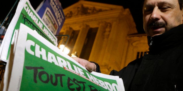 A newspaper seller installs Charlie Hebdo newspapers to a shelf at a newsstand in Nice, southeastern France, Wednesday, Jan. 14, 2015. In an emotional act of defiance, Charlie Hebdo resurrected its irreverent and often provocative newspaper Tuesday, featuring a caricature of the Prophet Muhammad on the cover that drew immediate criticism and threats of more violence. The black letters on the front page reads: "All is forgiven." (AP Photo/Lionel Cironneau)