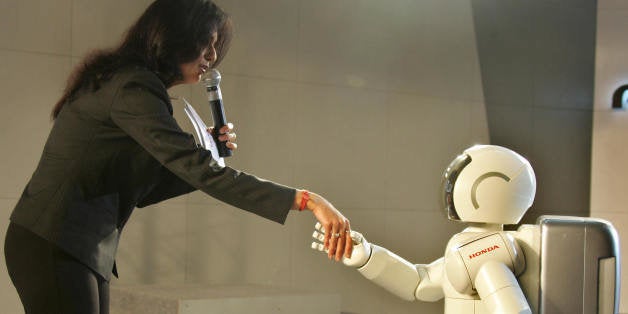 New Delhi, INDIA: An anchor at the Honda exhibition stall shakes hands with the robot ASIMO during the inauguration of 17th I