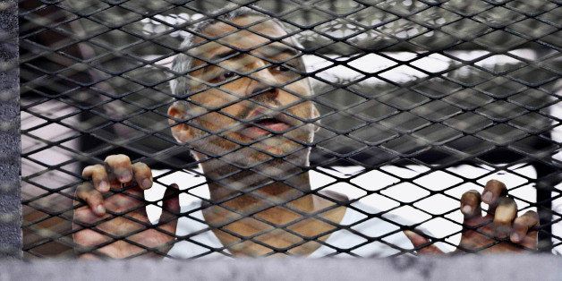 FILE - In this Thursday, May 5, 2014 file photo, Mohammed Fahmy, Canadian-Egyptian acting bureau chief of Al-Jazeera, appears in a defendant's cage at a courtroom in Cairo, Egypt. An Egyptian court on Monday, June 23, 2014, convicted three Al-Jazeera journalists and sentenced them to seven years in prison on terrorism-related charges after a trial dismissed by rights groups as a politically motivated sham. The verdict brought a landslide of international condemnation and calls for Egyptian President Abdel-Fattah el-Sissi to intervene. El-Sissi, on Tuesday said he will not interfere in court rulings, sparking an international outcry. (AP Photo/Hamada Elrasam, File)