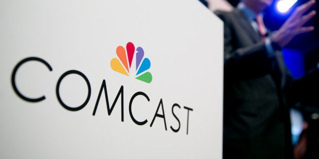 The Comcast Corp. logo is seen as Brian Roberts, chairman and chief executive officer of Comcast Corp., right, speaks during