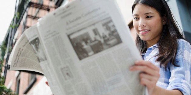 Asian woman reading newspaper