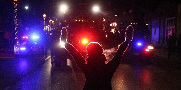 A protester raises her hands in the street as police use tear gas to try to take control of the scene near a Ferguson Police Department squad car after protesters lit it on fire on Tuesday, Nov. 25, 2014, in the wake of the grand jury decision not to indict officer Darren Wilson in the shooting death of Ferguson, Mo., teen Michael Brown. (Anthony Souffle/Chicago Tribune/TNS via Getty Images)