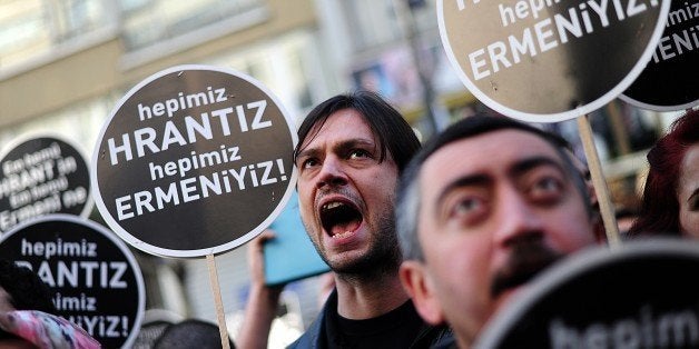 People hold placard reading ' we all are Hrant, We all are Armenians' as they shout slogans in front of Armenian newspaper 'Agos' during a commemoration ceremony for slain journalist Hrant Dink, in Istanbul, on January 19, 2015. Turkish riot police were out in force as large crowds massed in Istanbul to demand justice for a prominent Turkish Armenian journalist murdered eight years ago. Hrant Dink, one of the most prominent voices of Turkey's shrinking Armenian community, was killed by a gunman on January 19, 2007. The 52-year-old Dink, a prominent member of Turkey's tiny Armenian community, campaigned for reconciliation but was hated by Turkish nationalists for calling the World War I massacres of Armenians a genocide. AFP PHOTO /OZAN KOSE (Photo credit should read OZAN KOSE/AFP/Getty Images)