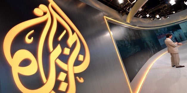 The Al Jazeera logo is seen in the new Al Jazeera America television broadcast studio on West 34th Street August 16, 2013 in New York as Paul Eedle (R), Deputy Launch Manager for Programing speaks to media during a tour. Al Jazeera America, which will launch on August 20, will have its headquarters in New York. AFP PHOTO/Stan HONDA (Photo credit should read STAN HONDA/AFP/Getty Images)