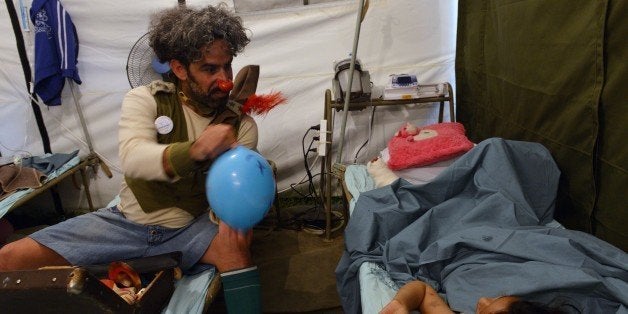 An Israeli medical clown entertains a Nepalese earthquake victim during a visit to a makeshift army camp in Kathmandu on May