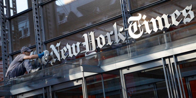 A man polishes the sign for The New York Times at the company's headquarters, July 18, 2013 in New York. The newspaper has fa