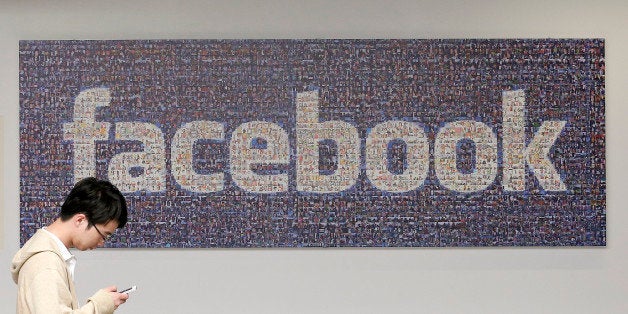 In this Wednesday, June 11, 2014 photo, a man walks past a sign in an office on the Facebook campus in Menlo Park, Calif. One