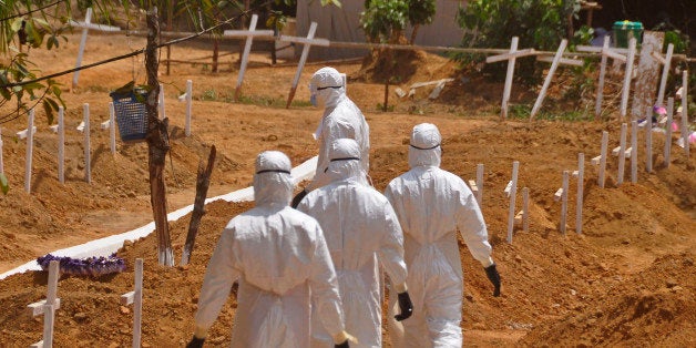 FILE- In this file photo dated Wednesday, March 11, 2015, health workers walk inside a new graveyard for Ebola victims, on the outskirts of Monrovia, Liberia. Despite the drop in reported Ebola cases, Dr. Bruce Aylward, leading WHOâs Ebola response, declared Friday April 10, 2015, that itâs too early for World Health Organization to downgrade the global emergency status of the biggest-ever Ebola outbreak in Africa. (AP Photo/Abbas Dulleh, FILE)