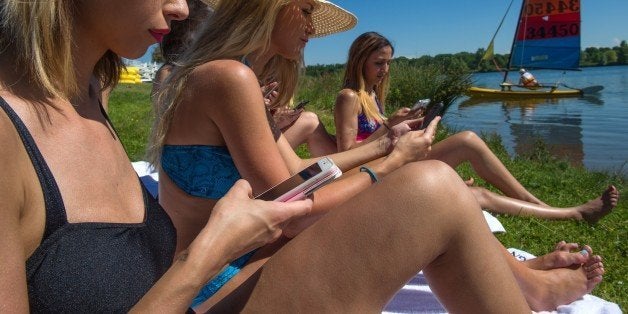 TO GO TO AFP STORY BY ARNAUD BOUVIERA model shows her smartphone with the connected interface during a photo session to present a new connected swimsuit collection by French company Spinali Design in Reiningue, eastern France, on June 4, 2015. AFP PHOTO / SEBASTIEN BOZON (Photo credit should read SEBASTIEN BOZON/AFP/Getty Images)