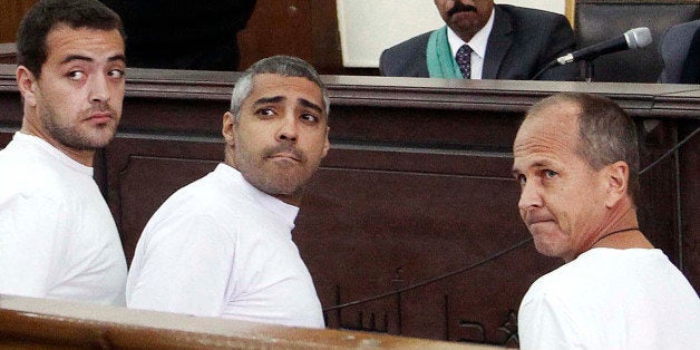 FILE - In this Monday, March 31, 2014 file photo, Al-Jazeera English producer Baher Mohamed, left, Canadian-Egyptian acting Cairo bureau chief Mohammed Fahmy, center, and correspondent Peter Greste, right, appear in court along with several other defendants during their trial on terror charges, in Cairo, Egypt. An Egyptian court on Monday, June 23, 2014, convicted three Al-Jazeera journalists and sentenced them to seven years in prison on terrorism-related charges after a trial dismissed by rights groups as a politically motivated sham. The verdict brought a landslide of international condemnation and calls for Egyptian President Abdel-Fattah el-Sissi to intervene. El-Sissi, on Tuesday said he will not interfere in court rulings, sparking an international outcry. (AP Photo/Heba Elkholy, El Shorouk, File) EGYPT OUT