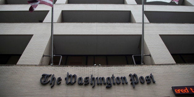 FILE - In this Aug. 6, 2013, file photo, an American flag, left, and a District of Columbia fly outside The Washington Post building in Washington. The longtime headquarters building of The Washington Post is being sold to a real estate development company for $159 million. Graham Holdings Co. is the former parent of The Washington Post newspaper. The company announced a deal Nov. 27, to sell the downtown Washington building to Carr Properties. (AP Photo/Evan Vucci, File)