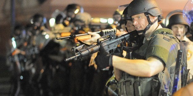 Law enforcement officers watch on during a protest on West Florissant Avenue in Ferguson, Missouri on August 18, 2014. Police fired tear gas in another night of unrest in a Missouri town where a white police officer shot and killed an unarmed black teenager, just hours after President Barack Obama called for calm. AFP PHOTO / Michael B. Thomas (Photo credit should read Michael B. Thomas/AFP/Getty Images)