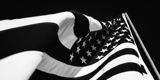 Abstract photograph of an American flag waving in the breeze very closeup. High contrast black and white. Stars and stripes visible. No people in photograph. Room for your content message at top of image. Horizontal composition.