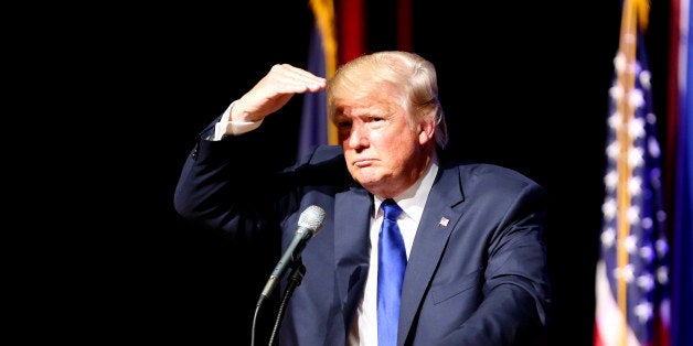 Republican presidential candidate Donald Trump shields his eyes from the lights as he takes a question from the crowd during a campaign town hall Wednesday, Aug. 19, 2015, at Pinkerton Academy in Derry, N.H. (AP Photo/Mary Schwalm)