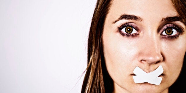 A beautiful brown-eyed young blonde with her mouth taped shut gazes out sadly. Appropriate for all women's issues, including