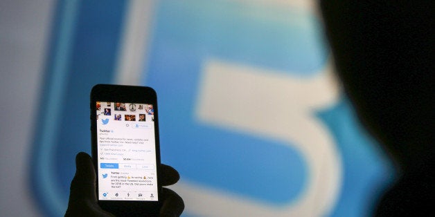 A man looks at the Twitter Inc. page on a mobile device whilst standing against an illuminated wall bearing Twitter Inc.s logo in this arranged photograph in London, U.K., on Tuesday, Jan. 5, 2016. Twitter Inc. may be preparing to raise its character limit for tweets to the thousands from the current 140, a person with knowledge of the matter said. Photographer: Chris Ratcliffe/Bloomberg via Getty Images