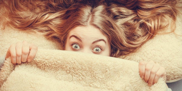 Woman waking up in bed in the morning after sleeping. Well rested young girl laying covering face with wool woolen blanket. Instagram filter.