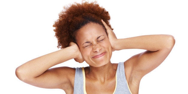 Portrait of an unhappy young female covering her ears over a white background