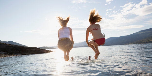 Young women jumping from dock into lake