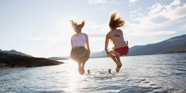 Young women jumping from dock into lake