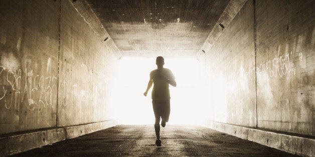 Caucasian man running in urban tunnel