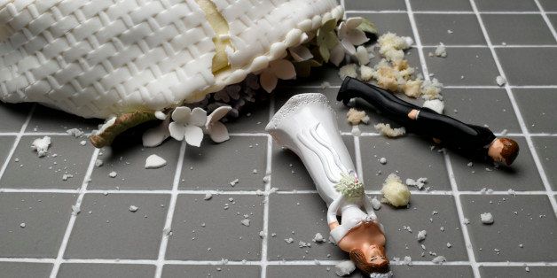 Bride and groom figurines lying at destroyed wedding cake on tiled floor