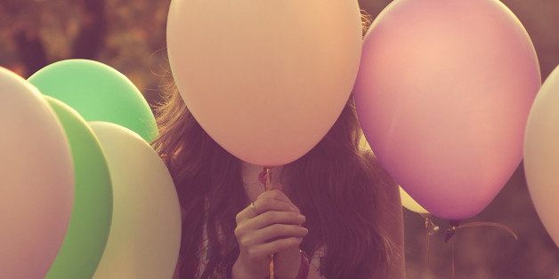 Girl hiding behind balloons.