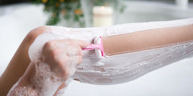 Woman shaving her legs in bathtub