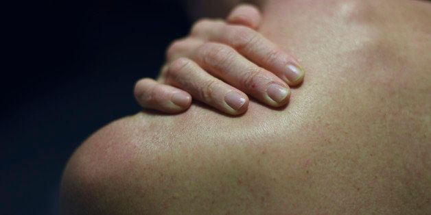 Woman's left shoulder with right hand resting on neck.