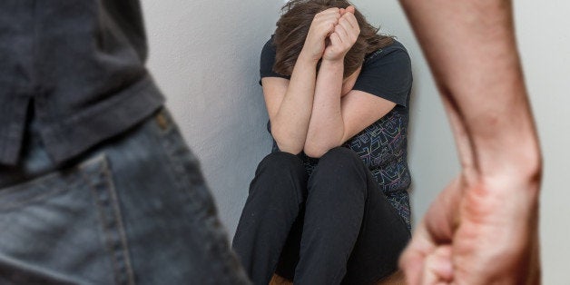 Fist of anger man and crying woman sitting in corner. Domestic violence and social concept.