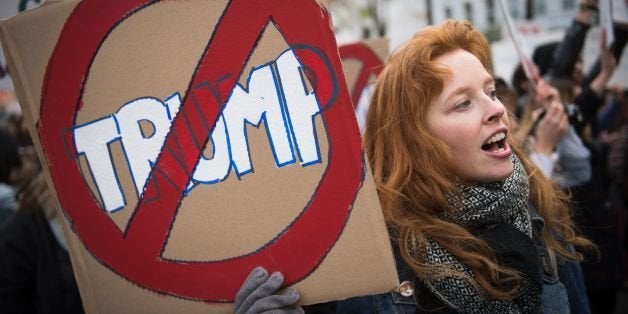 A woman holds a sign during a demonstration against US President-elect Donald Trump in Paris on November 19, 2016. / AFP / MARTIN BUREAU (Photo credit should read MARTIN BUREAU/AFP/Getty Images)