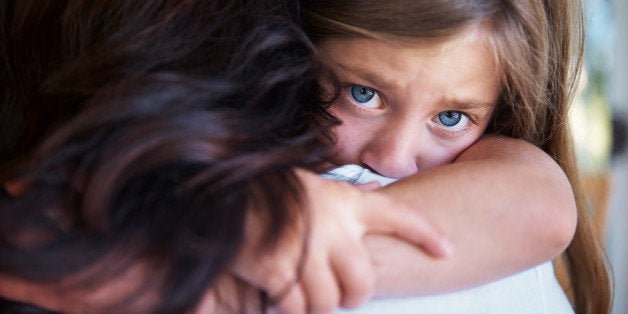 Closeup shot of a upset little girl hugging her mom around the neck