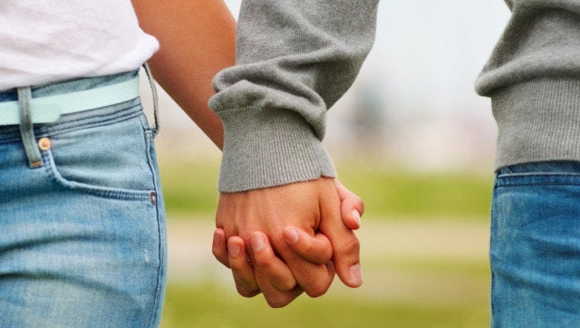 Mid section closeup image of a young couple holding hands, outdoors