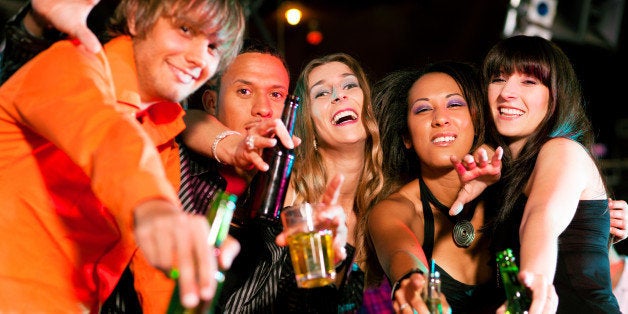 Group of friends - men and women of different ethnicity - having fun in a disco or nightclub