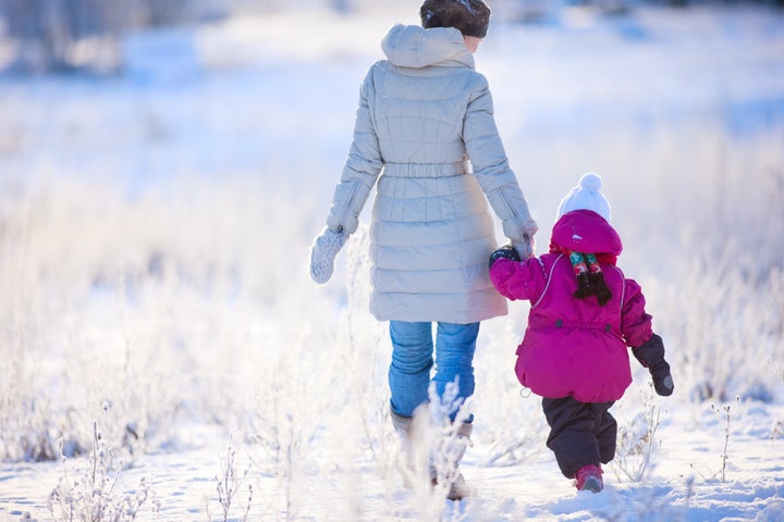 Back view of mother and daughter walking on winter day