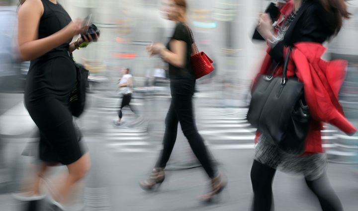 pregnant woman walking on the street, businesswomen walking by and female jogger in the background, intentional in camera motion blur